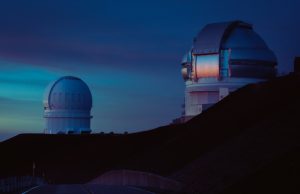 244 Exa-Electronvolt Cosmic Ray Defies Physics Limit A cosmic ray detection observatory in the Utah desert under a starry night sky, with a particle trail streaking toward the ground.