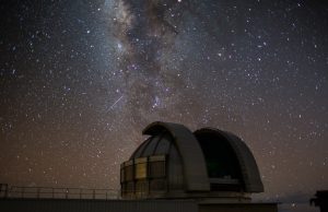 Graduate Student Discovers Newborn Exoplanet A graduate student points at a telescope image showing a newborn exoplanet in its early formation stage.