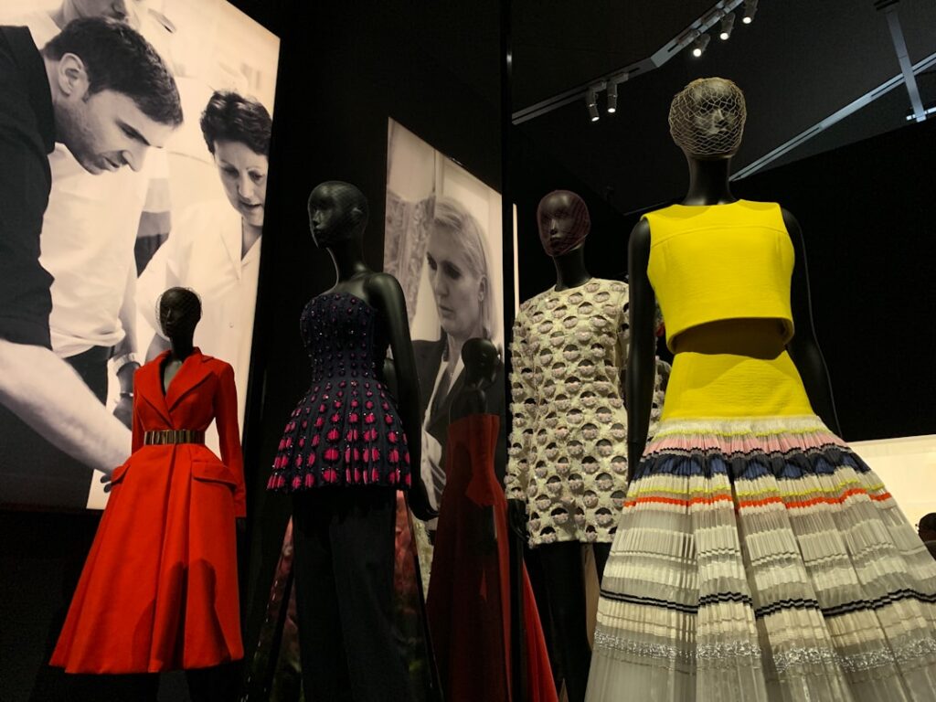 Visitors watch a holographic Victorian gown shimmer and sway inside the Anna Wintour Costume Center gallery.