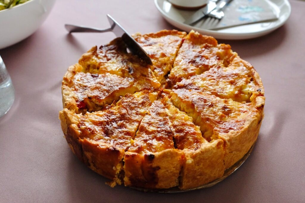 Royal chef Mark Flanagan presents the coronation quiche, a deep dish with spinach and broad beans, on a serving platter.